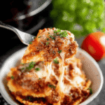 Fork lifting a cheesy serving of Crockpot Ravioli Lasagna Recipe with rich meat sauce and melted mozzarella