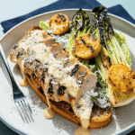 Grilled chicken Caesar salad with charred romaine, grilled lemon halves, creamy dressing, and Parmesan on toasted bread
