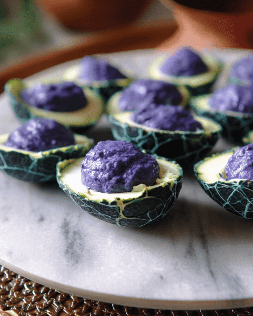 Plate of Halloween deviled eggs with eerie cracked green shells and spooky purple yolk filling.