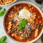 Hearty TikTok Lasagna Soup with ricotta, basil, curly noodles, and beef in a tomato broth served in a white bowl.