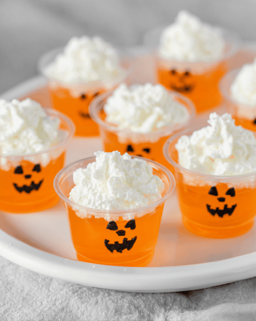 Assorted Jack-O-Lantern keto jello shots with whipped cream on a white plate