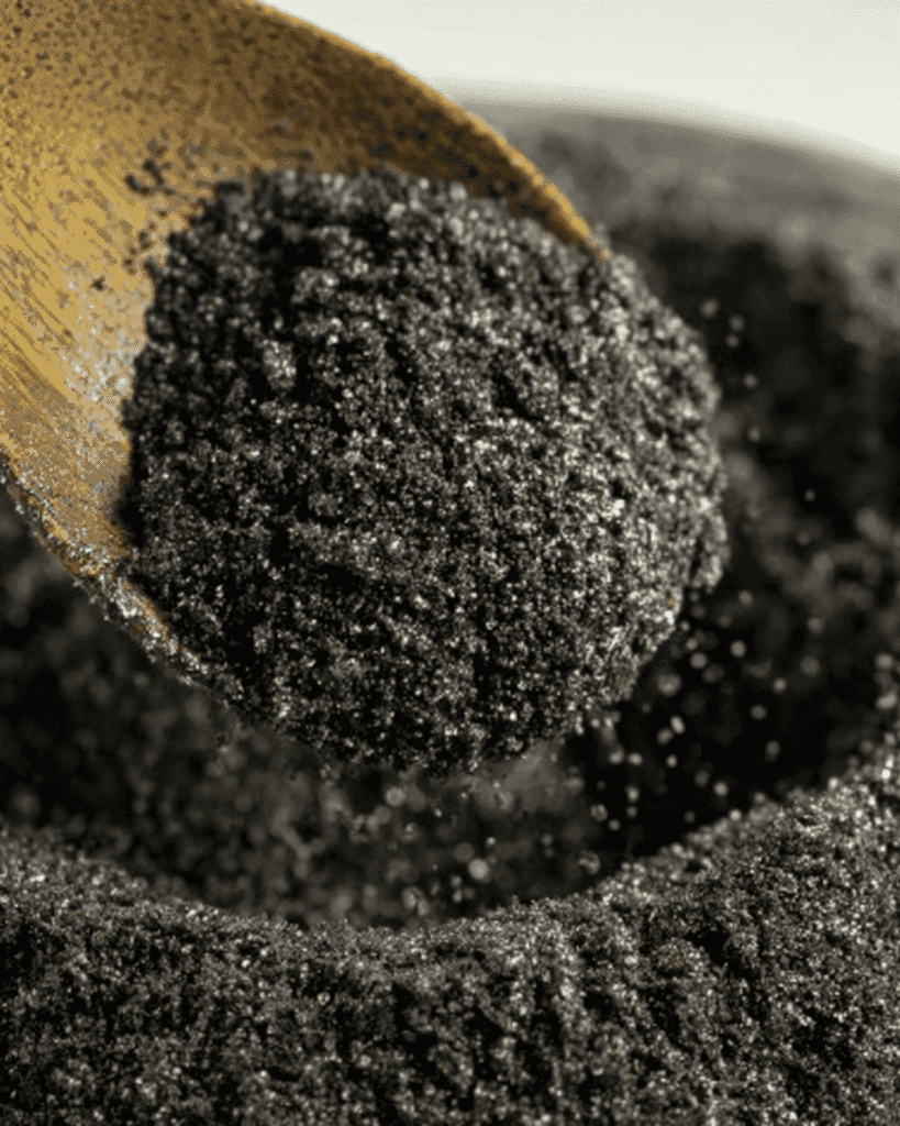 Black cocoa keto Oreo cookie crumbs in a bowl with wooden spoon for dirt cake crust.