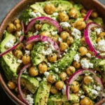Fresh chickpea feta avocado salad with red onions, parsley, and lemon herb dressing in a rustic bowl