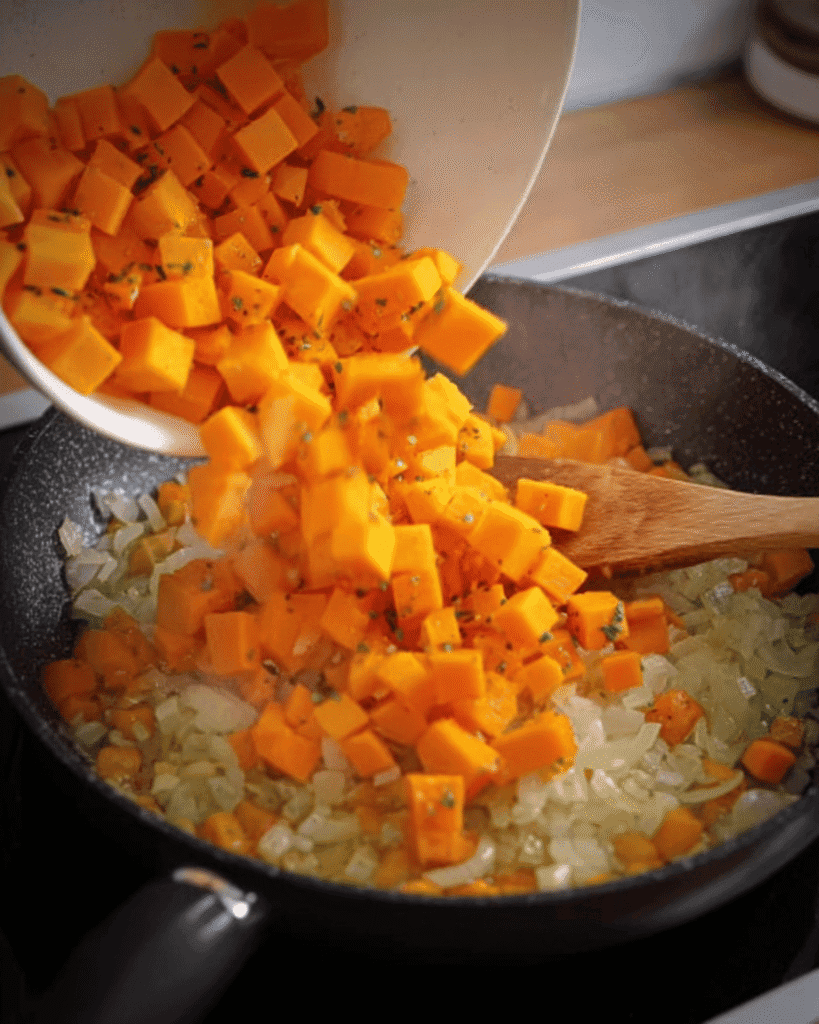 Diced pumpkin cubes and onions sautéing in a skillet for holiday meatloaf stuffing.