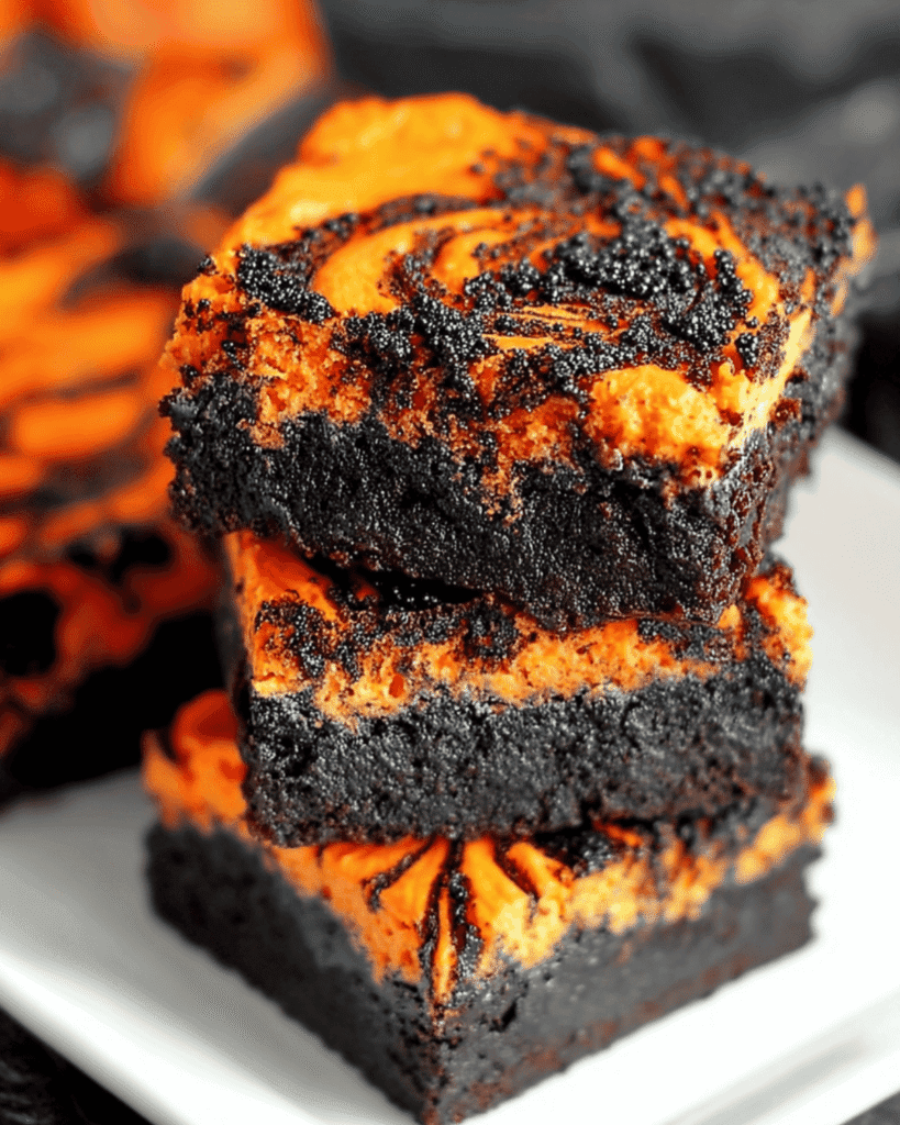 Two stacked Halloween swirl brownies with black and orange layers on a white plate