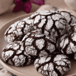Plate stacked with Spider Chocolate Crinkle Cookies coated in powdered sugar for the holidays.