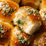 Fluffy homemade garlic bread roll topped with garlic butter and parsley being pulled apart