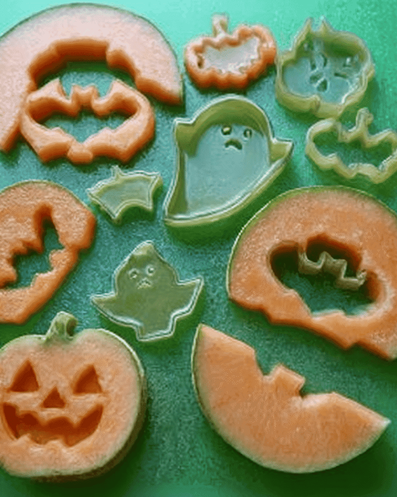 Halloween melon cutouts in pumpkin, ghost, and bat shapes for making festive fruit kabobs.