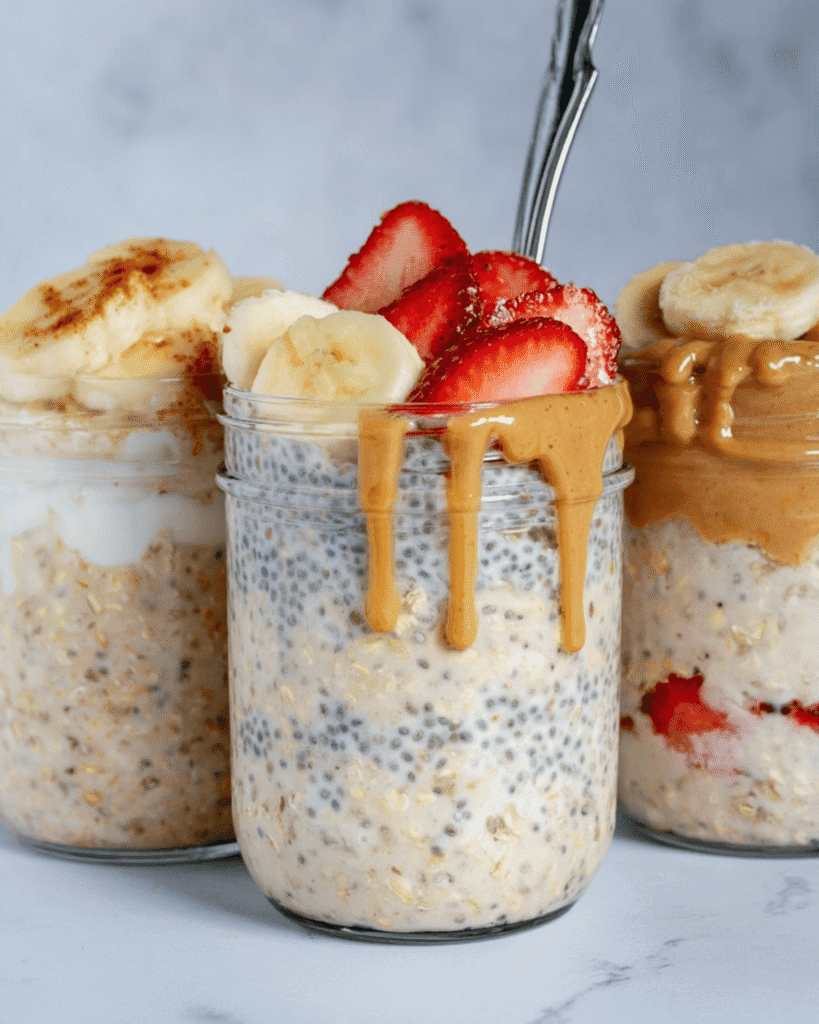 Three jars of overnight oats with chia seeds, topped with bananas, strawberries, and peanut butter