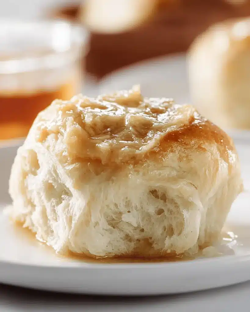 Fluffy Texas Roadhouse Roll topped with melting cinnamon honey butter on a white plate