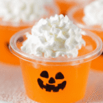 Close-up of Jack-O-Lantern keto jello shot with whipped cream topping in a clear cup