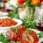 Braciole with Tomato Sauce served on a white plate with fresh parsley and rich Italian red sauce.