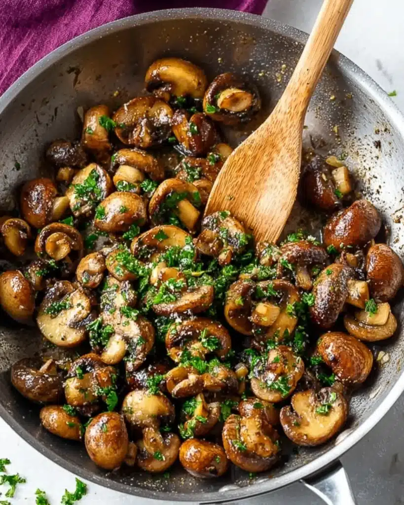 Sautéed baby bella mushrooms in a skillet with garlic and parsley