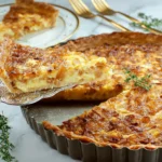Slice of Caramelized Onion Tart being lifted from a metal tart pan with golden crust and melted cheese