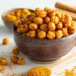 Close-up of spicy roasted chickpeas in a rustic wooden bowl with paprika and chili powder, a perfect healthy Thanksgiving appetizer