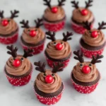 Easy Reindeer Cupcakes with chocolate frosting, red noses, and antlers arranged on a clean white background.