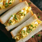 Close-up of fluffy Japanese egg sandwiches filled with creamy egg salad and sliced green onions.