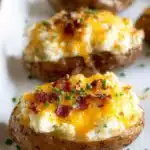 Close-up of golden twice baked potato topped with cheddar cheese, beef, and chopped chives