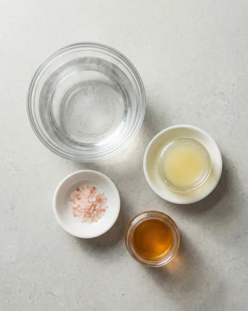 Bowls of water, pink salt, lemon juice, and apple cider vinegar for a pink salt drink.