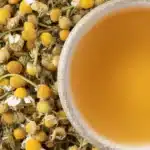 Top view of chamomile tea cup resting on a pile of dried chamomile buds.