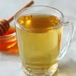 Green Tea Recipe in a clear glass mug with honey dipper, healthy green tea drink for weight loss
