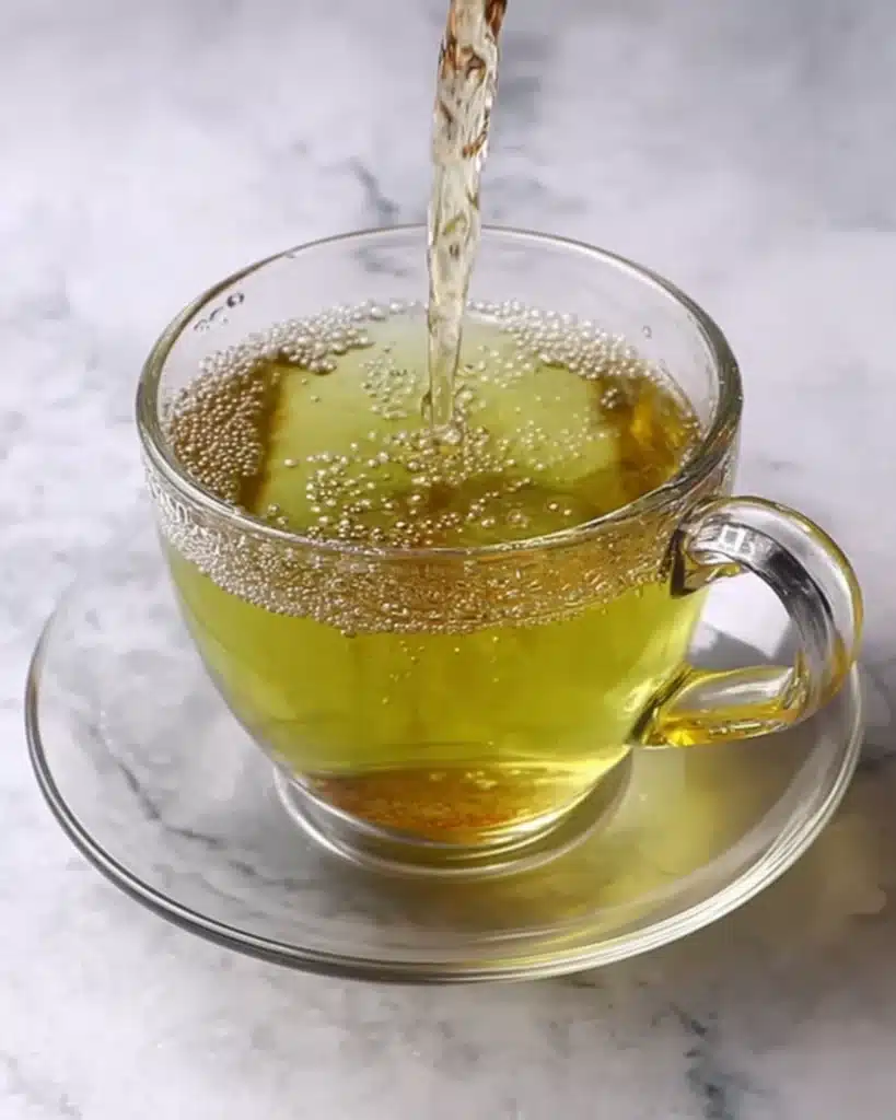 Green Tea Recipe being poured into glass cup on saucer, simple homemade green tea for wellness