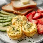 Breakfast plate with egg bites, avocado, strawberries, and toasted bread