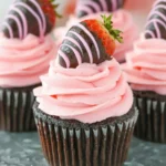Close-up of frosted chocolate cupcake with strawberry buttercream and chocolate-dipped strawberry