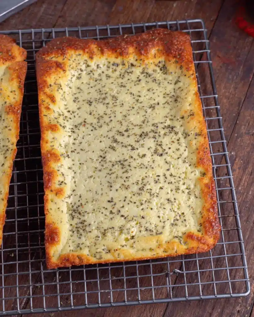 Golden-brown cottage cheese flatbread cooling on a wire rack with chili flakes in the background