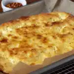 Herb-seasoned baked flatbread with golden edges cooling on a rack