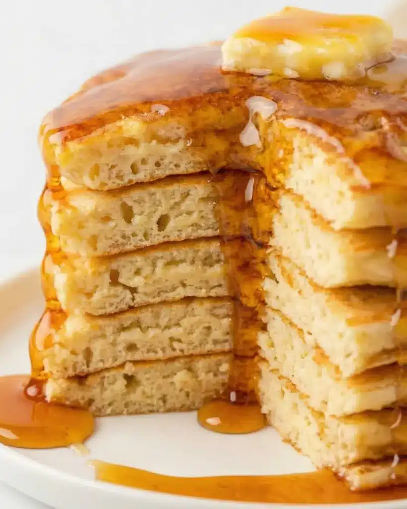Stacked pancakes cut open to reveal soft interior layers soaked with maple syrup