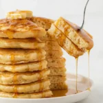 Fork lifting a soft pancake slice with syrup dripping from the fluffy interior