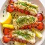 Butterflied lobster tails topped with garlic herb butter and fresh parsley served with lemon wedges