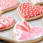 Heart shaped cookies featuring marbled and polka dot icing patterns in pink and red