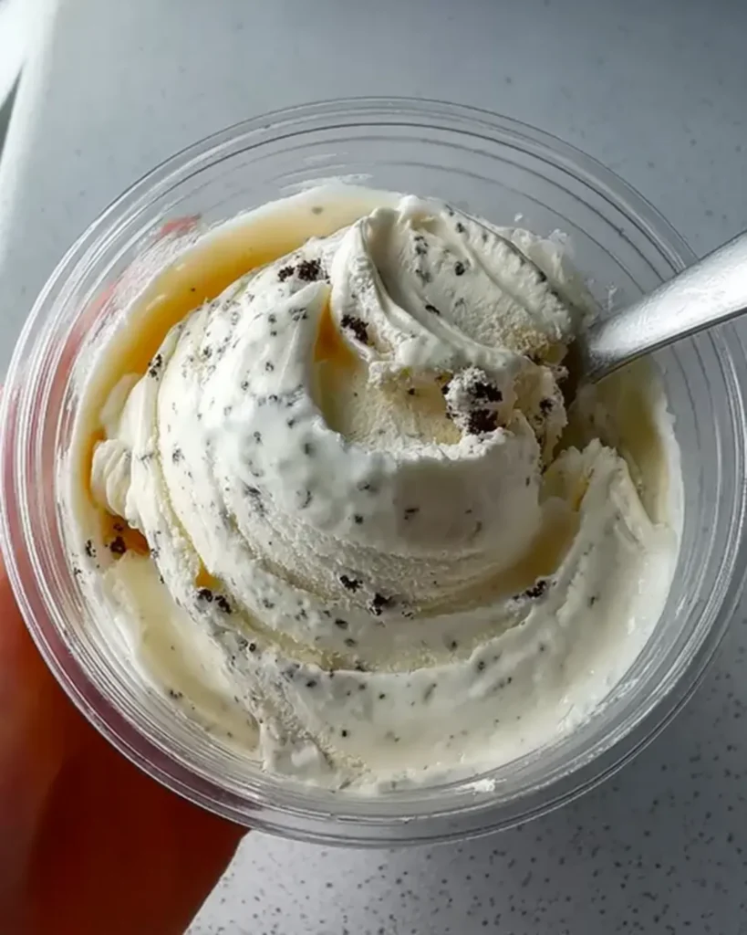 Creamy vanilla ice cream with chocolate cookie specks in a clear pint.