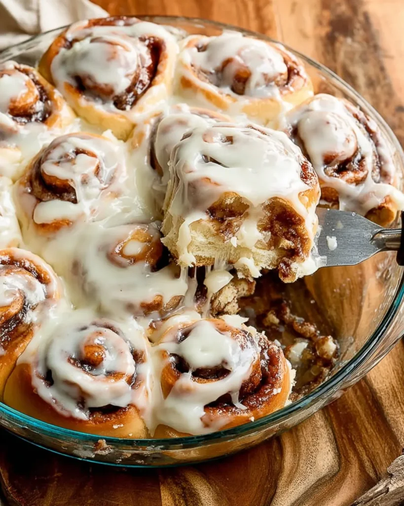 Best cinnamon rolls lifted from baking dish showing gooey cinnamon sugar filling