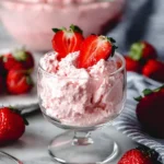 Fluffy fruit and cottage cheese dessert in a clear serving glass with fresh strawberries