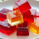 Close up of Knox gelatin recipe cubes in red and amber colors on a white plate