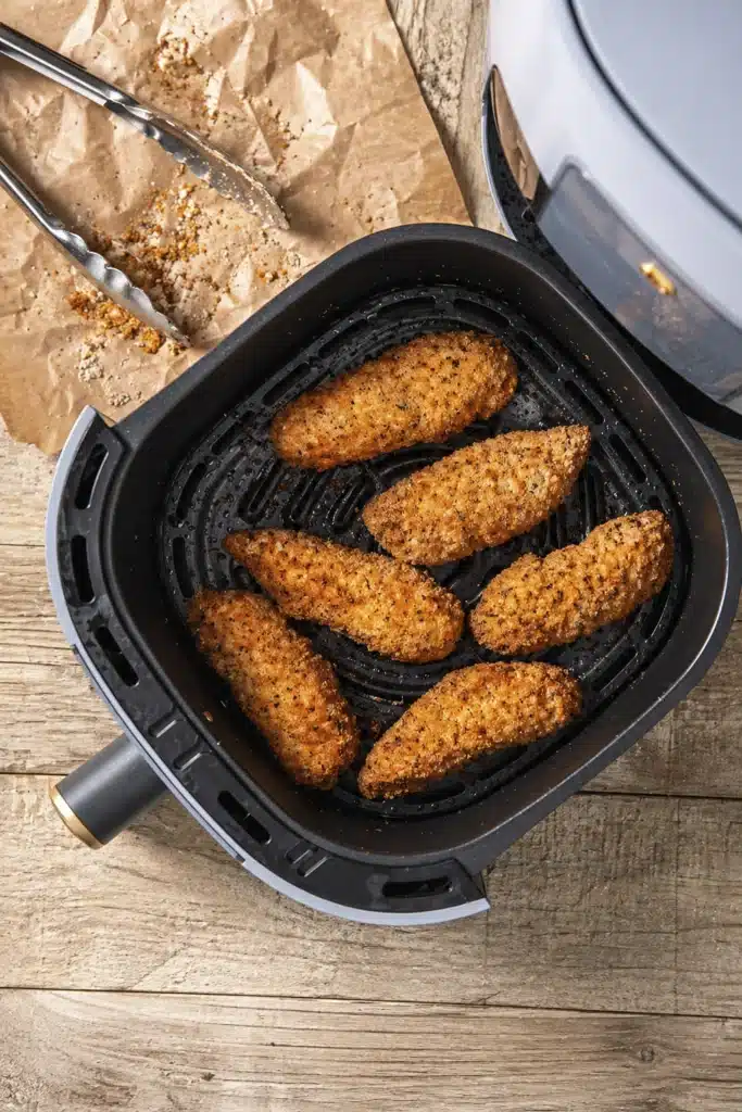 Crispy Air Fryer Chicken Tenders cooking inside an air fryer basket with golden breaded coating