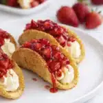 plated cheesecake tacos with creamy filling and strawberry topping on white serving dish