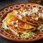 Cheesy potato tacos with crispy corn tortillas topped with tomato sauce, queso fresco, and shredded lettuce