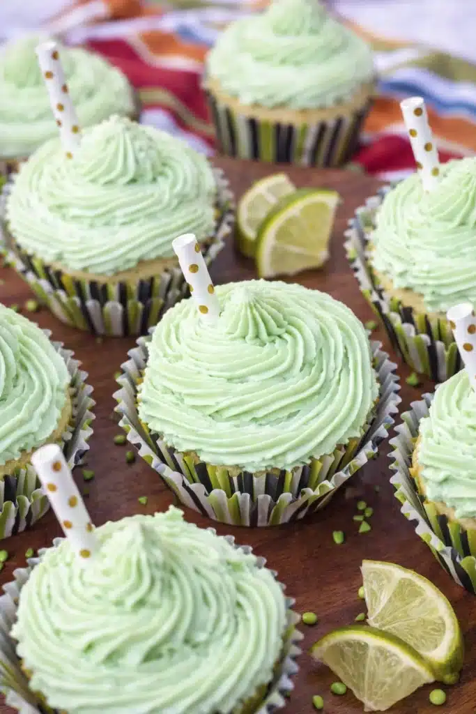 Margarita cupcakes with tequila lime frosting arranged on a tray with lime wedges and festive decorations