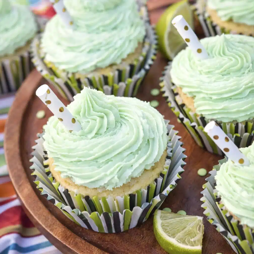 Margarita cupcakes with tequila lime buttercream frosting topped with decorative straw and fresh lime slice