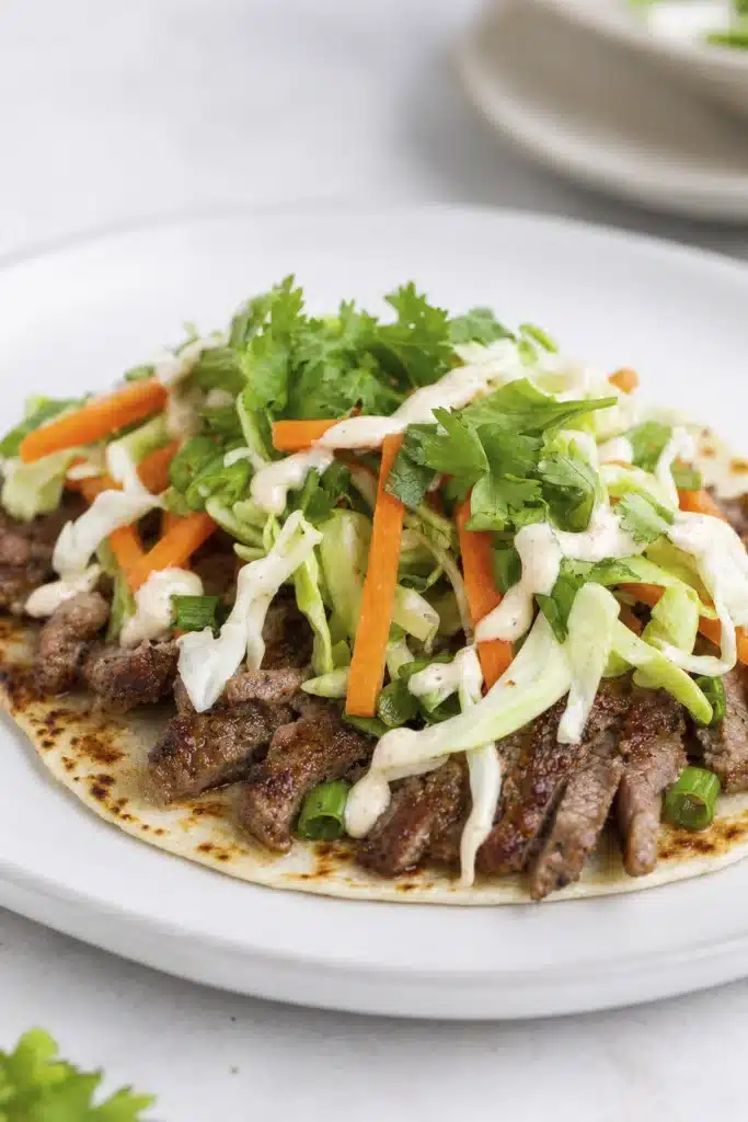 Smash dumpling tacos topped with cabbage carrots cilantro and creamy sauce