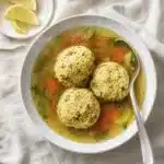 Ultimate Matzo Ball Soup served in bowl with fresh herbs and golden broth