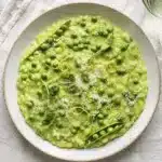 creamy green pea risotto in pan with arborio rice parmesan and fresh peas