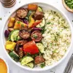 Close up of easy air fryer chicken sausage and veggies with zucchini, bell peppers, onions, and couscous