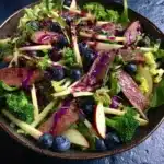 Fresh salad with beef slices, blueberries, apple sticks, and purple dressing