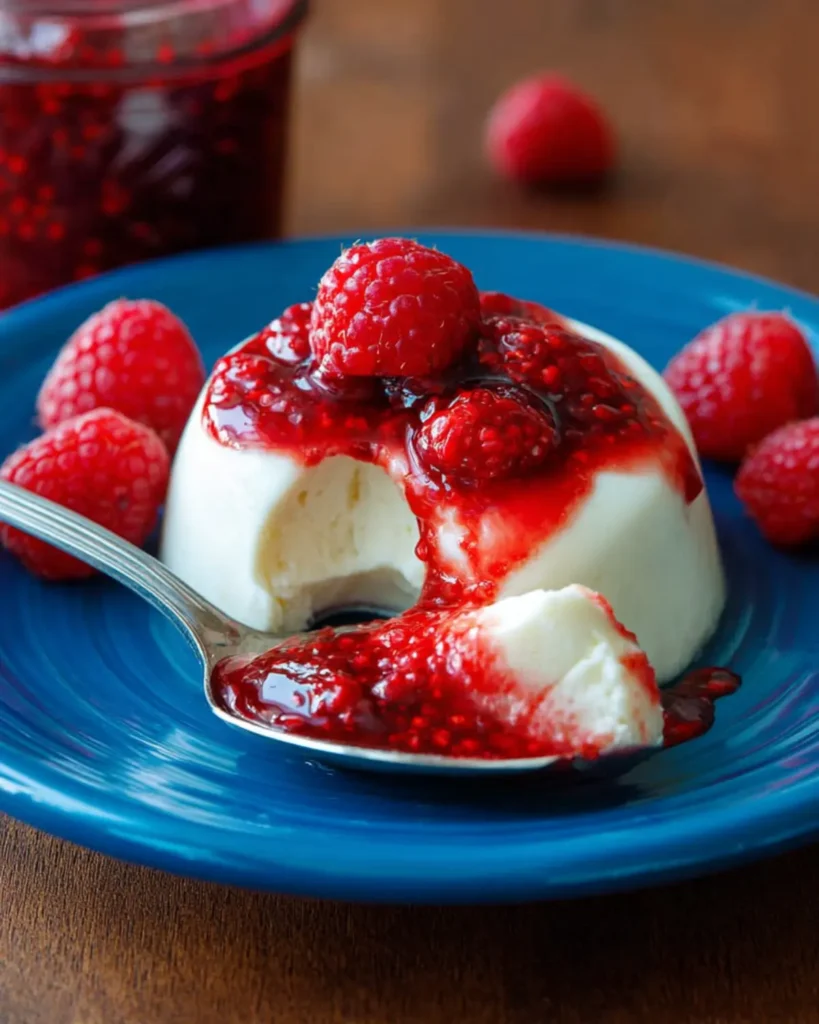 Panna cotta dessert with a spoonful taken showing creamy texture and berry topping