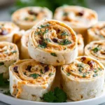 Stacked tortilla rolls with creamy filling and herbs on a serving plate